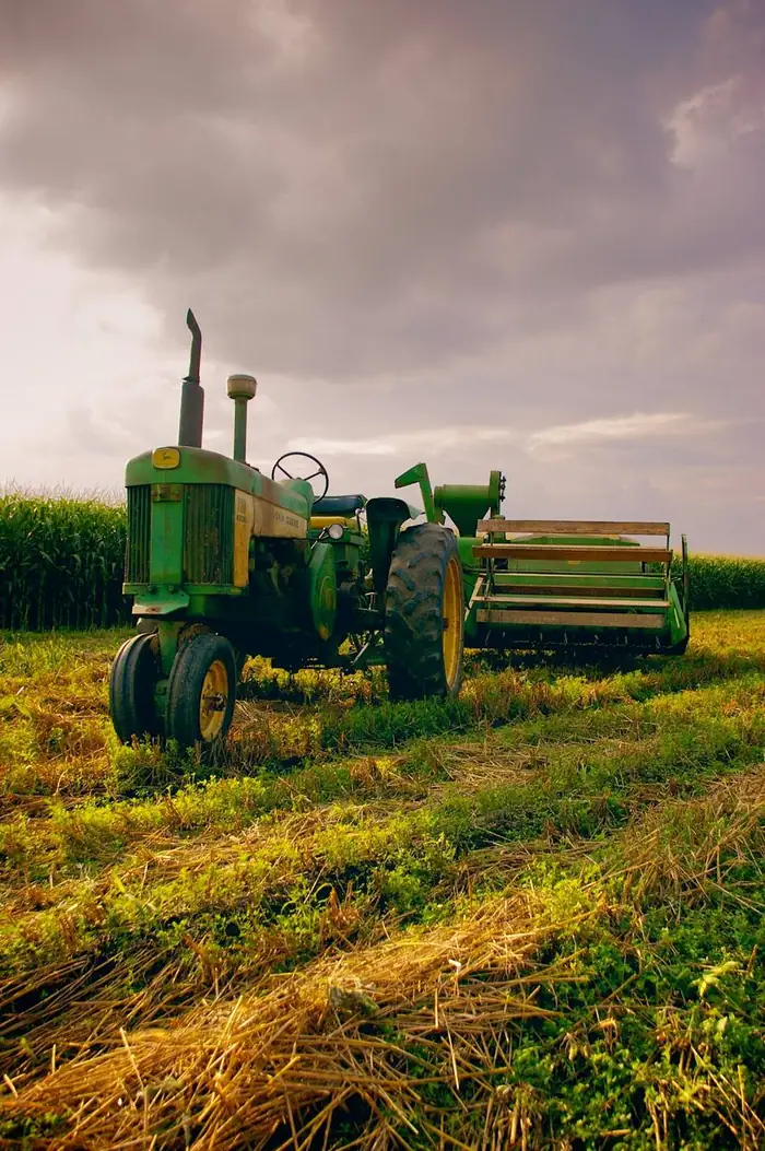 Tractor agrícola verde estacionado junto a un maizal